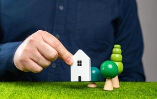 A man places a house figurine on a plot of land. Build a new house on the plot. Develop or use the land for residential purposes. Buying a property. photo