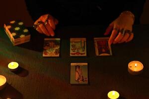 KYIV, UKRAINE - JULY 10, 2024 Tarot reader picking tarot cards. Candlelight in dark room. Tarot reader or fortune teller reading and forecasting photo