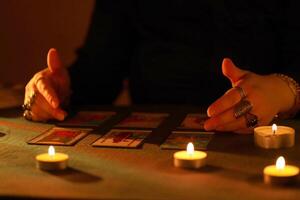 KYIV, UKRAINE - JULY 10, 2024 Tarot reader picking tarot cards. Candlelight in dark room. Tarot reader or fortune teller reading and forecasting photo