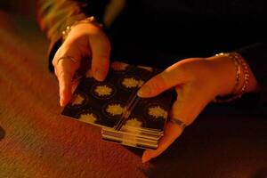 KYIV, UKRAINE - JULY 10, 2024 Tarot reader picking tarot cards. Candlelight in dark room. Tarot reader or fortune teller reading and forecasting photo