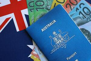 KYIV, UKRAINE - JULY 10, 2024 Australian blue travel passport and money bills on Australia flag background photo