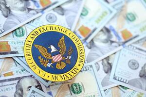 KYIV, UKRAINE - JUNE 26, 2024 U.S. Securities and Exchange Commission coat of arms on big amount of US dollar banknotes photo