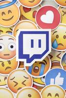 KYIV, UKRAINE - APRIL 20, 2024 Twitch logo and large set of stickers with Emoji yellow faces. Emoji is a pictogram or smiley embedded in text and used in electronic messages photo