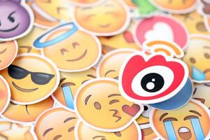 KYIV, UKRAINE - APRIL 20, 2024 Weibo logo and large set of stickers with Emoji yellow faces. Emoji is a pictogram or smiley embedded in text and used in electronic messages photo