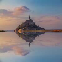 Panoramic view of the famous Le Mont Saint-Michel abbey reflected in high tide at sunset photo
