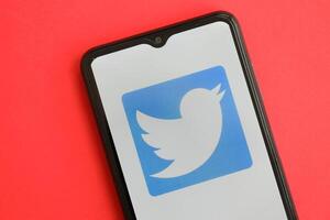 KYIV, UKRAINE - APRIL 1, 2024 Twitter icon on smartphone screen on red table photo