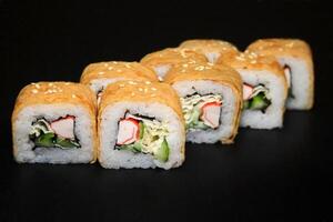 Sushi roll with omelet and crab on black background. photo
