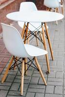 Empty white table and chair on the street near the cafe. Urban decor. photo