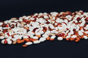 View from above. multi-colored beans scattered on a black background. background with space for text photo