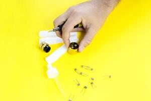 electronic cigarette details, Vata, coils, drip, spring, nippers on a yellow background. man's hands change springs in vape photo
