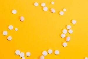 Different pills and vitamins are scattered on a yellow background. space for text photo