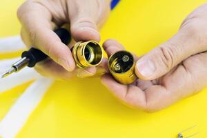 electronic cigarette details, Vata, coils, drip, spring, nippers on a yellow background. man's hands change springs in vape photo