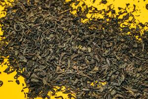 large leaf green tea scattered on a yellow background. close-up photo