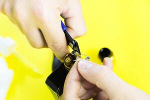 electronic cigarette details, Vata, coils, drip, spring, nippers on a yellow background. man's hands change springs in vape photo