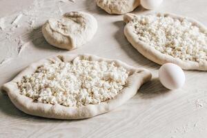 Homemade Ajarian Khachapuri with Suluguni Cheese Close Up. Stage of work. Raw Suluguni before baking photo