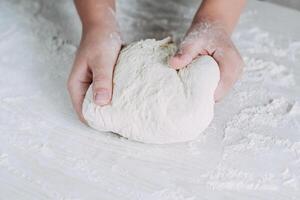 Making dough by female hands on white wooden table background. photo