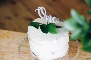 cake decorated with a sprig of greens and a wooden inscription one. cake for 1 year to the child photo