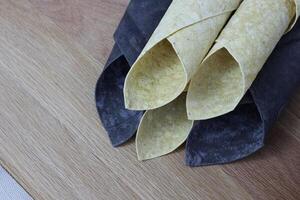 thin pita bread white and black rolled up in a straw with greens. Chorny pita with cuttlefish ink and Armenian traditional pita photo