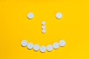 face with a smile laid out with pills and vitamins on a yellow background photo