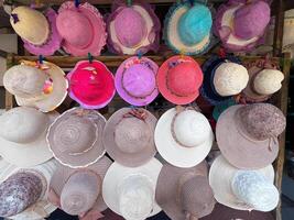 A row of hats are displayed on a rack, with a variety of colors and styles. The hats are arranged in a way that makes it easy for customers to browse and photo