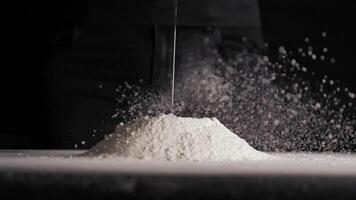 Chicken egg falls in slow motion into flour on black isolated background close up in 4K video