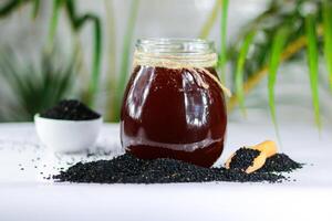 Honey in a glass jar with black cumin seeds on a table photo