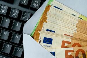 European banknotes in an envelope lying on a computer keyboard. photo