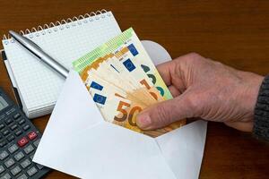 Man's hand holding european banknotes from an envelope. photo