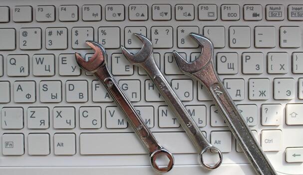 Computer Support Concept Stock Photo. Three Steel Spanners Lying On Bilingual Keyboard photo