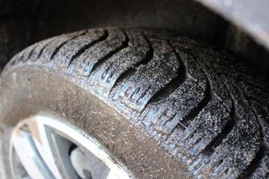 The car's all season tire is covered in mud photo