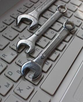 Metallic wrenches on a buttons of laptop keyboard vertical stock photo. Different types of hardware concept image photo