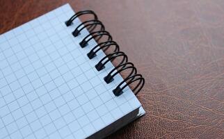 Unopened spiral notebook on leather table stock photo for title or business logo