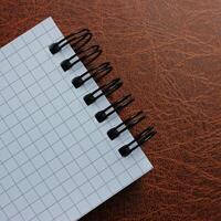 Square Image Of Bound Notepad With White Page On Leather Surface photo