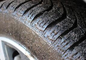 A car tire completely covered with a layer of liquid mud closeup view photo