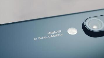 Close-up of a smartphone showcasing a 48MP AI dual camera design on a reflective surface photo