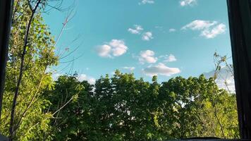 Through the window of an abandoned building you can see the sky and greenery in sunny weather photo