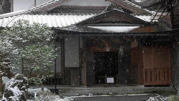 landscape view of old architecture temple of Kurama temple in Kyoto japan while snow is falling covered surface of the roof and floor video