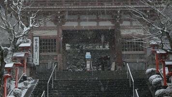 view to Kuramadera temple with rock stair pathway leads to main entrance gate of the temple while snowing snow falling in winter time video