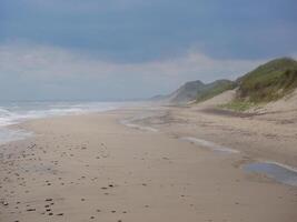 Scenic view of the sea and sand dune on the beach on a gloomy, cloudy weather, Skagen, Denmark photo