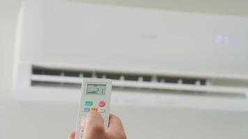 Adjusting air conditioner temperature with remote control. Hand holds remote control and setting comfortable temperature on climate system in apartment video