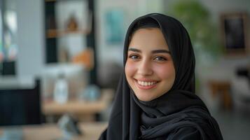 Cheerful Female Saudi Influencer Smiling and Wearing Black Hijab in Modern Setting photo