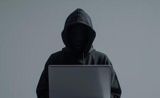 Anonymous Hooded Figure Using Laptop for Cybersecurity or Hacking in Dark Environment photo