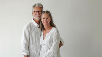 Middle-Aged Couple Smiling and Holding Hands Against a Neutral Background photo