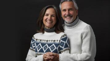 Middle-Aged Couple Smiling and Holding Hands in Warm Sweaters Against Black Background photo