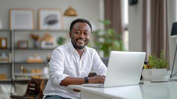 Smiling Man in White Shirt Working on Laptop at Office Desk photo