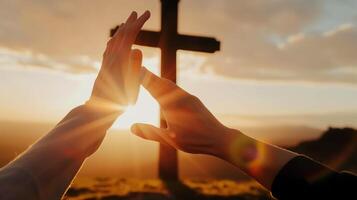 Close-Up of Hands Reaching for Each Other with a Cross and Sunset Background photo