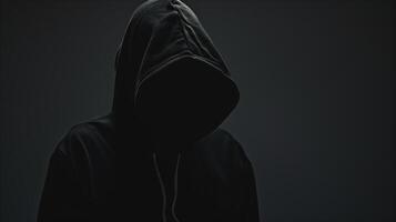 Anonymous Man in Black Hoodie with Hooded Face Evoking Mystery and Intrigue in Dark Setting photo