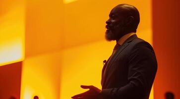 Dynamic Inspirational Speaker Delivering an Engaging Presentation in a Bright Orange Auditorium Setting photo