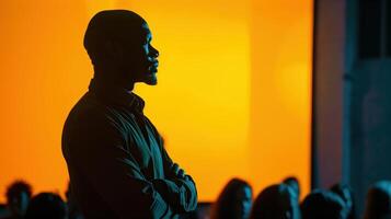 Inspirational Speaker Silhouetted Against Vibrant Orange Background During Motivational Conference photo