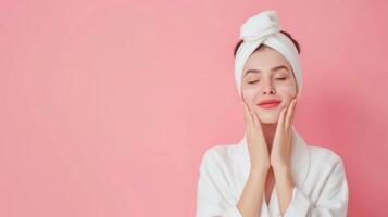 Woman Relaxing with Skin Care Routine in White Robe and Towel Turban Against a Pink Background photo
